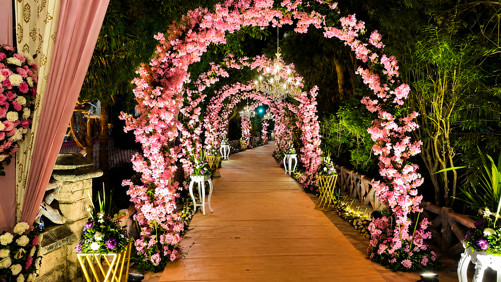 Wedding entrance pathway with fairy-light curtains, pampas grass and maroon pillars