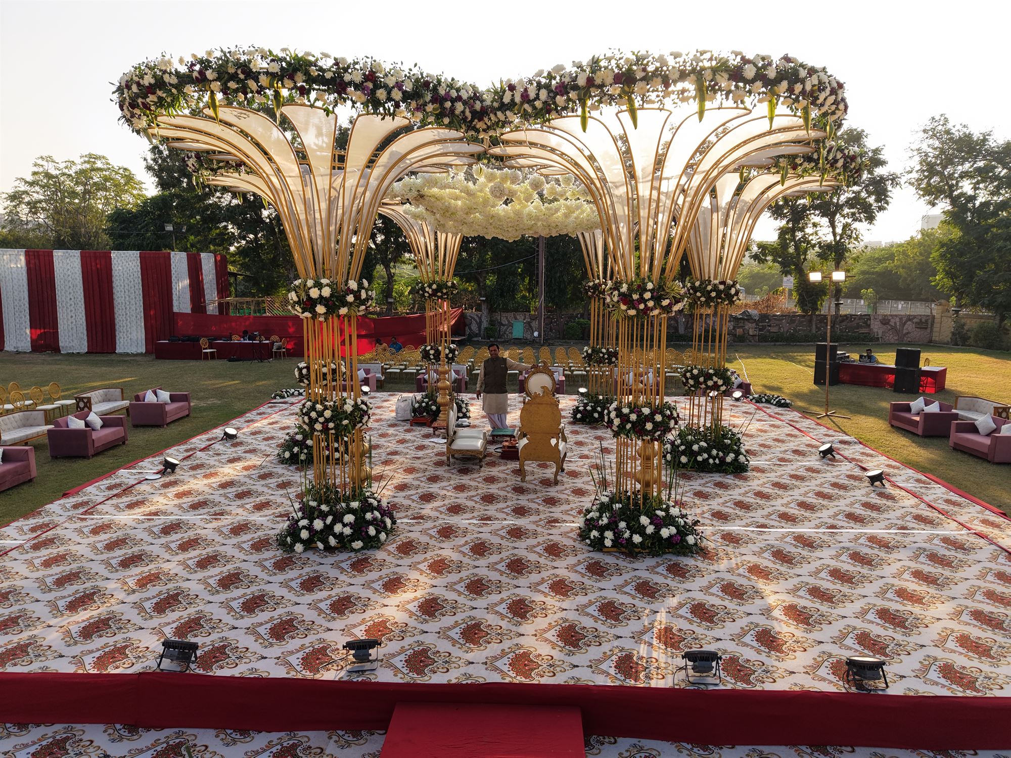 Gold fan mandap with white floral crowns at sunset, Prasang Party Plot, Ahmedabad