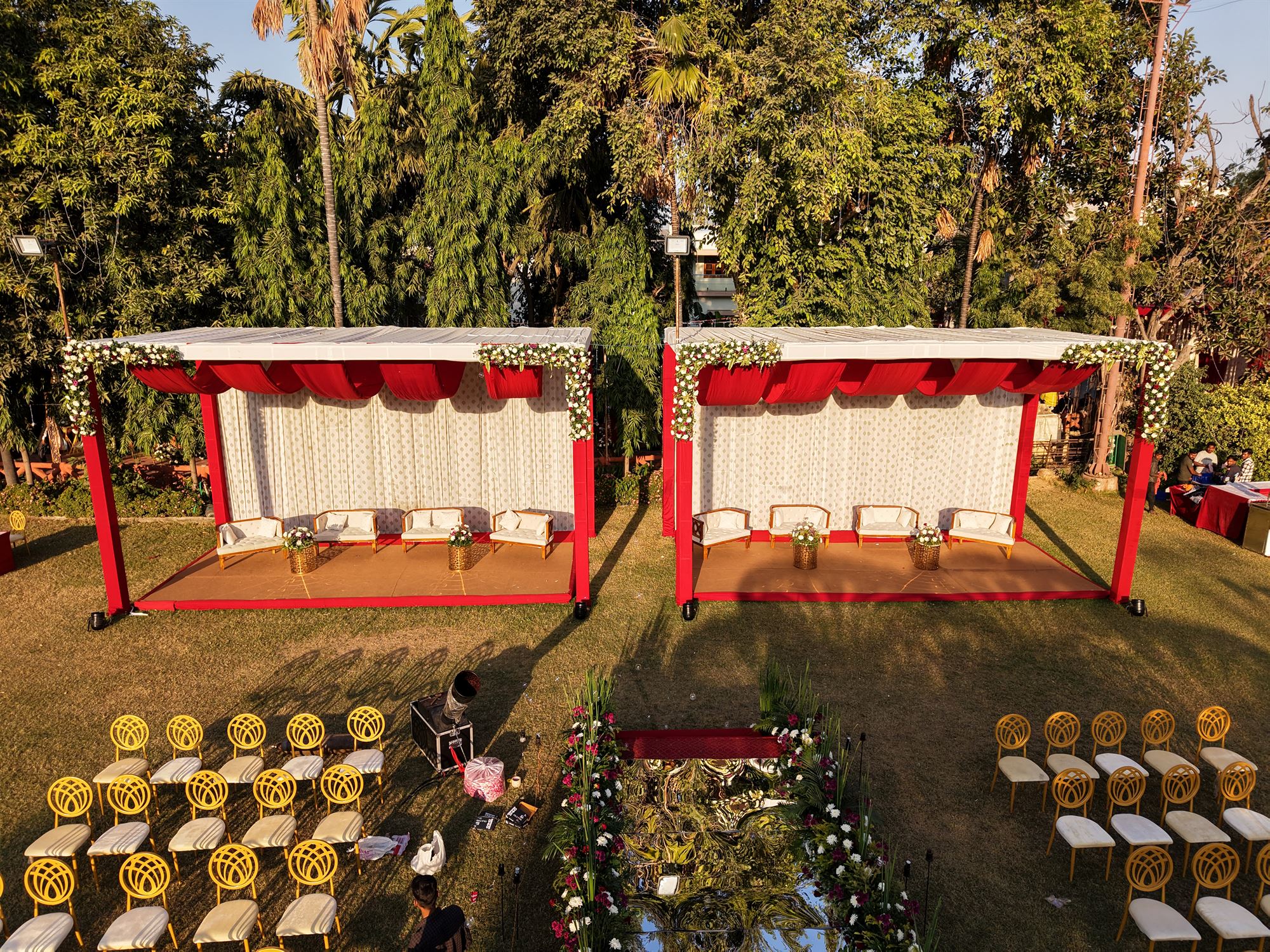 Twin red-canopy family pavilions with white lounge seating on a wedding lawn