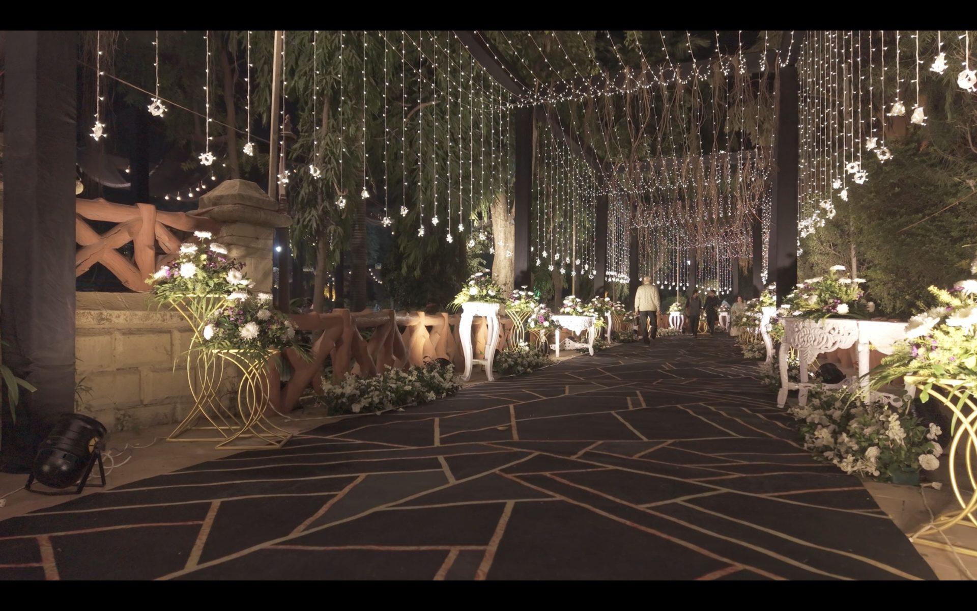 Fairy-light canopy walkway over a carved console at an intimate celebration